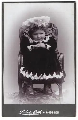 Fotografie Ludwig Orth, Giessen, Portrait kleines Mädchen im Samtkleid auf Stuhl sitzend