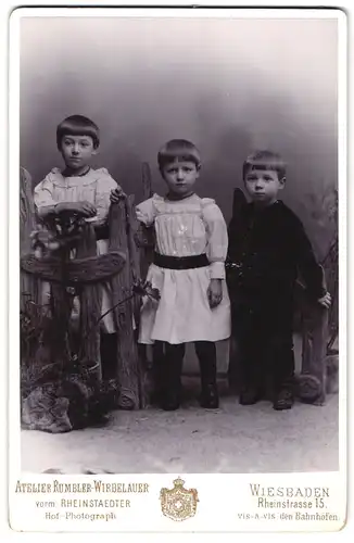 Fotografie Rumbler-Wirbelauer, Wiesbaden, Rheinstrasse 15, Portrait zwei kleine Mädchen und Junge in hübscher Kleidung