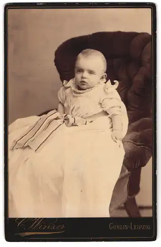 Fotografie C. Winzer, Leipzig-Gohlis, Portrait niedliches Kleinkind im weissen Kleid dauf Sessel sitzend