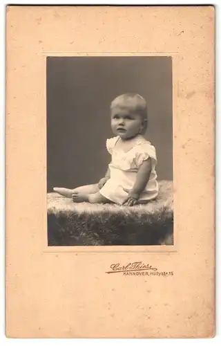 Fotografie Carl Thies, Hannover, Höltystrasse 15, Portrait niedliches Baby im weissen Hemd auf Fell sitzend