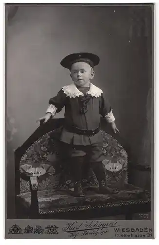Fotografie Karl Schipper, Wiesbaden, Rheinstrasse 31, Portrait kleiner Junge in hübscher Kleidung auf Bank stehend