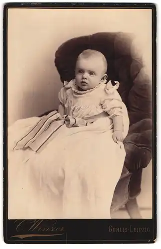 Fotografie C. Winzer, Leipzig-Gohlis, Leipzigerstrasse 7, Portrait niedliches Baby im weissen Kleid auf Sessel sitzend