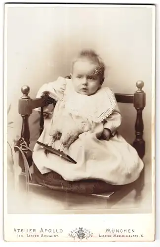 Fotografie Alfred Schmidt, München, Maximilianstrasse 6, Portrait niedliches Baby im weissen Kleid mit Spieltier