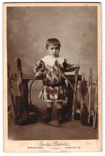 Fotografie Gustav Bödecker, Hamburg-St. Pauli, Reeperbahn 130, Portrait modisch gekleidetes Kind mit Reifen