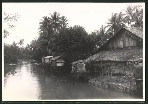 Fotografie Hoffmeister, Coblenz, Ansicht Sumatra, Pfahlhütte neben einem Flusslauf