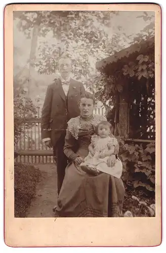 Fotografie unbekannter Fotograf und Ort, Portrait bürgerliches Paar mit Kleinkind im Garten