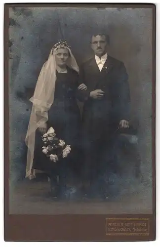 Fotografie Atelier Lienhardt, Einsiedeln, Portrait bürgerliches Paar in Hochzeitskleidung mit Blumenstrauss