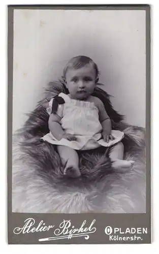 Fotografie Atelier Birkel, Opladen, Kölnerstrasse, Portrait niedliches Kleinkind im weissen Hemd auf Fell sitzend