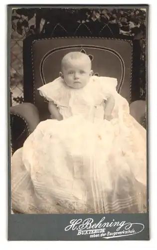 Fotografie H. Behning, Buxtehude, Portrait niedliches Baby im weissen Kleid auf Sessel sitzend
