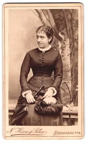 Fotografie N. Horn & Sohn, Sonneberg i. Th., Rosengasse, elegante junge Frau im schwarzen Kleid mit Sonnenschirm und Hut