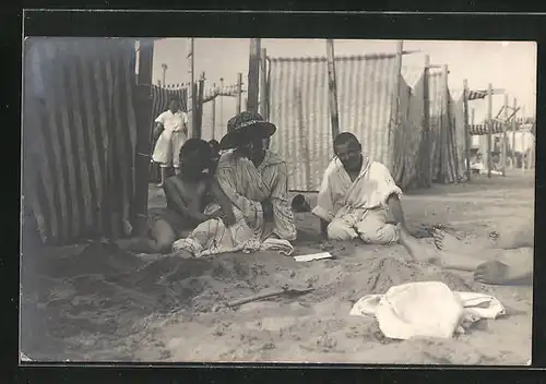 Foto-AK Familie sitzt im Halbschatten am Strand - Bademode