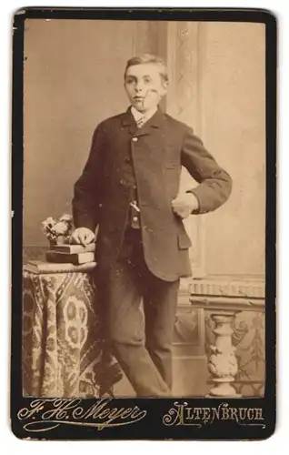 Fotografie F. H. Meyer, Altenbruch, Junger Mann mit Scheitelfrisur in feinem Anzug an einem Tisch lehnend