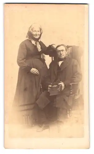 Fotografie unbekannter Fotograf und Ort, Portrait älteres Ehepaar mit dicker Bibel in der Hand