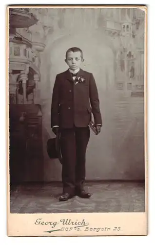 Fotografie Georg Ulrich, Hof i. B., Bergstr. 23, Portrait Junge im Anzug mit Hut vor einer Studiokulisse