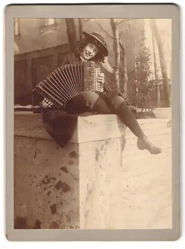 Fotografie unbekannter Fotograf und Ort, Portrait junge Frau mit Akkordeon sitzt auf einer Mauer