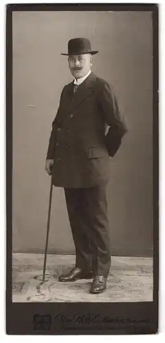 Fotografie MAx Höfele, München, Dachauer-Str. 25, Portrait Mann in dunklem Anzug mit Melone und Gehstock