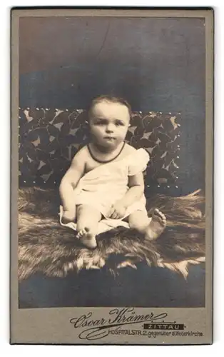 Fotografie Oscar Krämer, Zittau i. S., Hospitalstr. 2, Portrait niedliches Kleinkind mit Perlenhalskette im Hemdchen