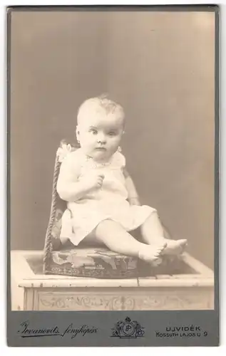 Fotografie P. Jovanovits, Neusatz, Hauptgasse 9, Portrait niedliches Kleinkind im weissen Kleid mit nackigen Füssen