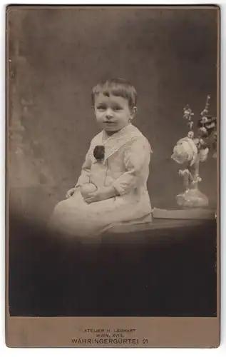 Fotografie H. Lebhart, Wien, Währingergürtel 21, Portrait kleines Mädchen im hübschen Kleid auf Tisch sitzend