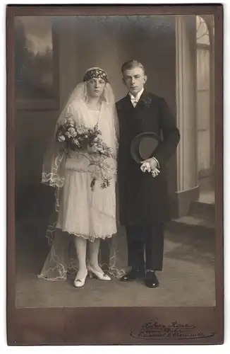 Fotografie Ludwig Roux, Einsiedel, Portrait junges Paar in Hochzeitskleidung mit Schleier und Blumenstrauss