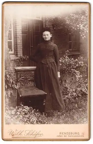 Fotografie Wilhelm Schäfer, Rendsburg, Ansicht Rendsburg, betagte Dame im schwarzen Kleid vor ihrem Haus