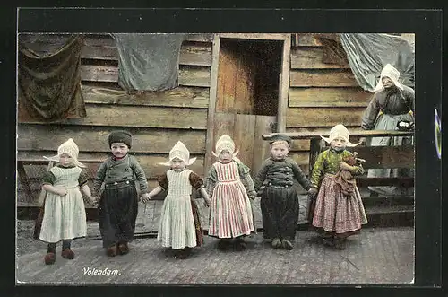 AK Voldendam, Holländische Kinder in einer Reihe, Im Hintergrund alte Frau