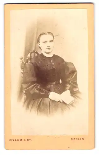 Fotografie Pflaum & Co., Berlin, Königs-Strasse 31, Portrait sitzende Dame im Sonntagskleid mit einem Buch