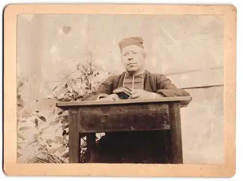 Fotografie Geistlicher mit Bibel an einem Tisch sitzend