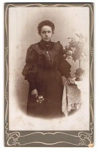 Fotografie unbekannter Fotograf und Ort, Portrait bürgerliche Dame mit Blume an Tisch gelehnt