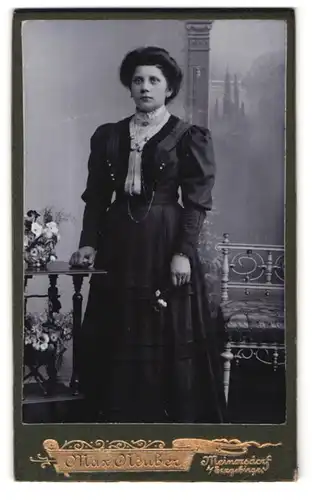 Fotografie Max Neuber, Meinersdorf i / Erzgebirge, Portrait bürgerliche Dame mit Blume an Tisch gelehnt