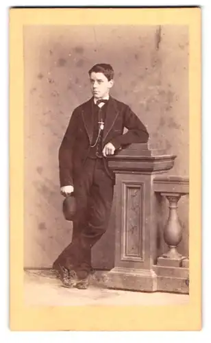 Fotografie F. Brandseph, Stuttgart, Portrait junger Mann im feinen Anzug mit Melone lehnt an Geländer