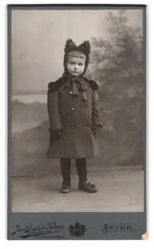 Fotografie Jean Baptiste Feilner, Oldenburg i. Gr., Rosenstr. 29, Portrait kleines Mädchen im Stoffmantel mit Ohrenmütze