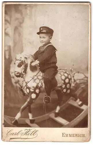 Fotografie Carl Hill, Emmerich, Portrait kleiner Junge im Matrosen Anzug mit Schaukelpferd