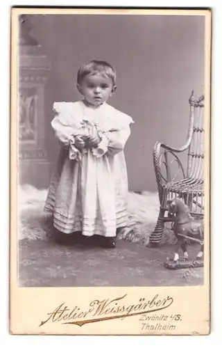 Fotografie Atelier Weissgärber, Zwönitz i / S., Portrait niedliches Kleinkind im weissen Kleid mit Spielzeugpferd