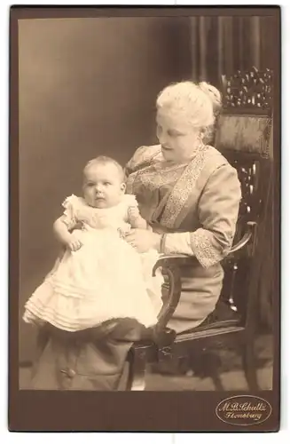 Fotografie M. B. Schultz, Flensburg, Portrait ältere Dame im hübschen Kleid mit Kleinkind auf dem Schoss