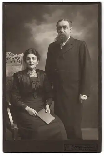 Fotografie J. Grimm, Offenburg, Portrait älteres Paar in hübscher Kleidung mit Buch