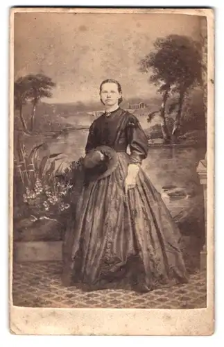 Fotografie Newell, York, Portrait junge Frau im seidenen Kleid mit Sommerhut vor einer Studiokulisse