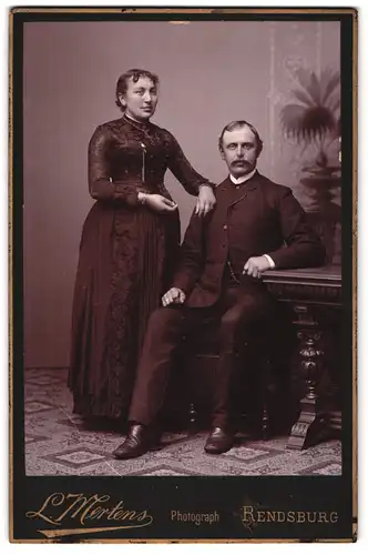 Fotografie L. Mertens, Rendsburg, Portrait bürgerliches Paar in hübscher Kleidung
