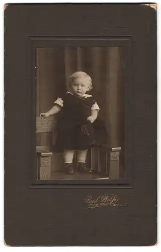Fotografie Paul Weiss, Melle, Portrait kleinem Mädchen im Samtkleid auf Stuhl stehend