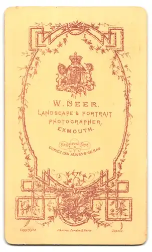 Fotografie W. Beer, Exmouth, Portrait älteres Paar im Anzug mit Fliege und Sommerkleid mit Blumenhaarschmuck