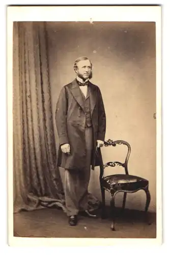 Fotografie R. C. May, Chelsea, 6 Sloane Terrace, Portrait junger Mann im Anzug mit Fliege und Backenbart