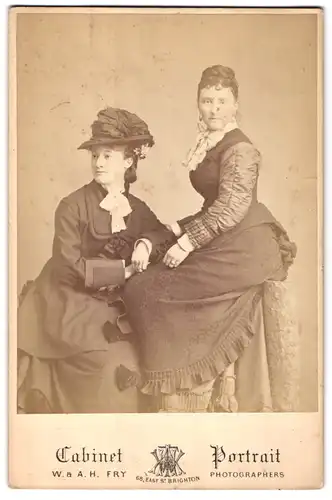 Fotografie W. & A. H. Fry, Brighton, 68 East St., Portrait zwei Damen in Biedermeierkleidern mit Hut und Hochsteckfrisur
