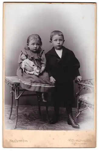 Fotografie Billström, Kiel, Holstenstrasse 43, Portrait Kinderpaar in modischer Kleidung mit Puppe