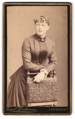 Fotografie Carl Dittmar, Landshut, Portrait modisch gekleidete Dame an Stuhl gelehnt