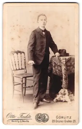 Fotografie Otto Fachte, Görlitz, Grüner Graben 29, Junger Bursche im Anzug lehnt auf einem Tisch