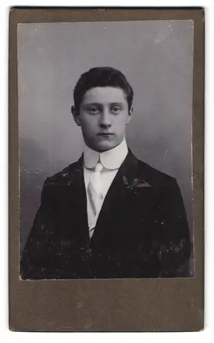 Fotografie Fotograf und Ort unbekannt, Portrait Bursche im dunkelen Anzug mit weisser Krawatte