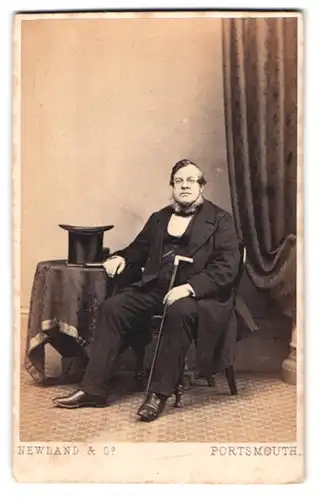 Fotografie Newland & Co., Portsmouth, Portrait korpulenter Mann mit Anzug mit Gehstock und Zylinder