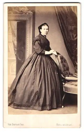 Fotografie John Burton & Sons, Leicester, Dame mit grosser Brosche trägt schwarzes Biedermeierkleid