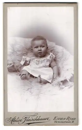 Fotografie Atelier Fleischhauer, Essen-Ruhr, Vereinstrasse 38, Portrait kleines Baby im Kleidchen auf einem Fell