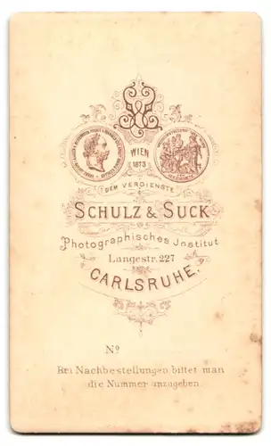 Fotografie Schulz & Suck, Carlsruhe, Langstr. 227, Dame in Kleid mit Zierfalten sitzt an Tisch und trägt Ohrringe